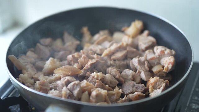 Diced pork being stir-fried in a hot frying pan with visible steam, capturing the home cooking process and freshly prepared ingredients. Ideal for culinary, recipe, and food preparation concepts