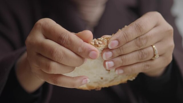 Hands breaking bread in a simple kitchen setting