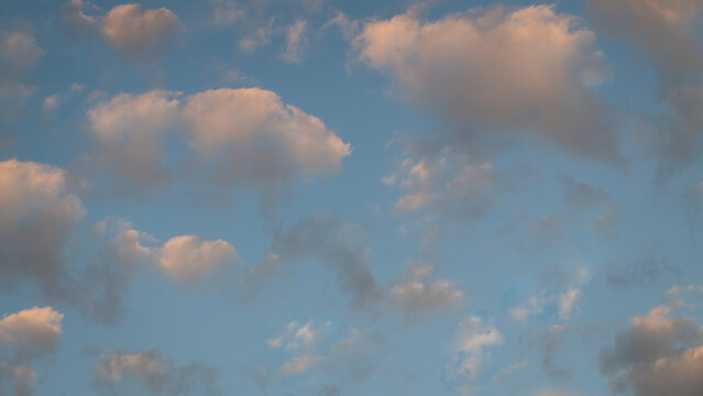 seamless background with pastel blue sky and white and grey clouds at sunset or sunrise