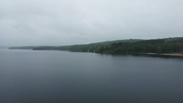 Aerial view of Commanda Lake with calm dark waters and dense forest shoreline under an overcast sky in Restoule, Ontario, Canada.