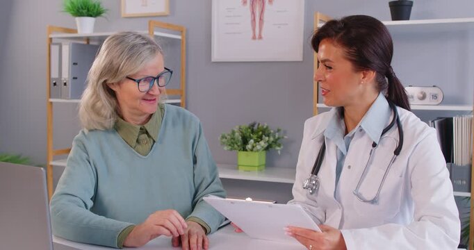 Doctor or nurse consulting with a senior woman patient during a medical visit, offering healthcare assistance, support, and discussing treatment and health concerns in a hospital setting.