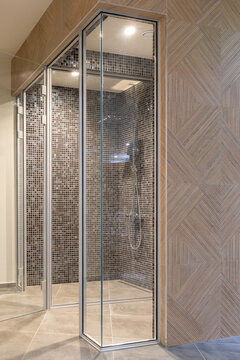 glass shower and steam room enclave featuring dark mosaic tile interior and a geometric wooden wall pattern in a luxury spa