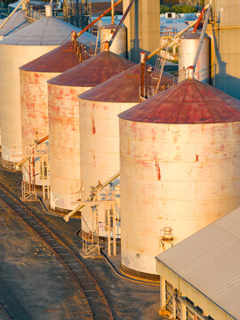 Aerial view of golden sunshine on a row of grain silos along a regional railway line