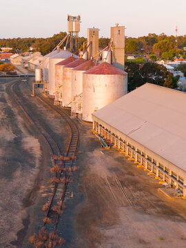 Aerial view of golden sunshine on a row of grain silos along a regional railway line