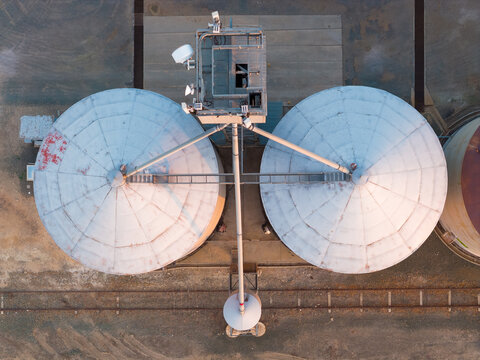 Aerial view over the top of a row of grain silos along a regional railway line