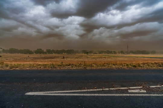 A summer dust storm approaching over country roads and dry farmland