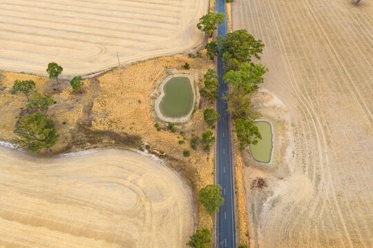 Aerial view of farm dams in dry paddocks along a country road