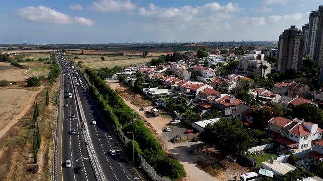 Slow Clockwise Rotating Aerial View of Rehovot Ring Road Between Green Fields and City Towers Under Clear Blue Summer Sky Central Israel