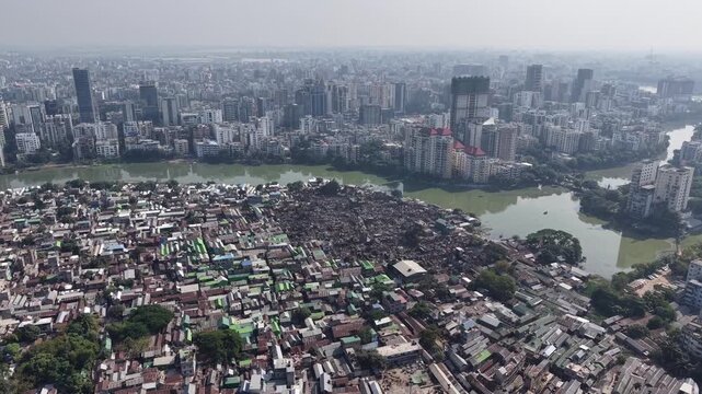Drone perspective of a burned section in a dense slum beside a modern city lake