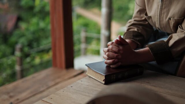 A young woman sits praying to God with her Bible, asking for a peaceful healing in her life healed by love and His holy word