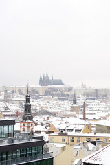 Naklejka premium Snowy rooftops shine. Cathedral dominates skyline. Winter cityscape inspires. Prague panorama captivates.