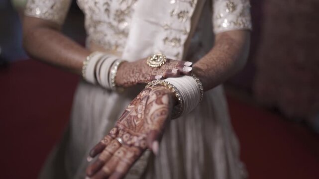 Indian bride showing intricate henna hands and traditional jewelry at wedding ceremony