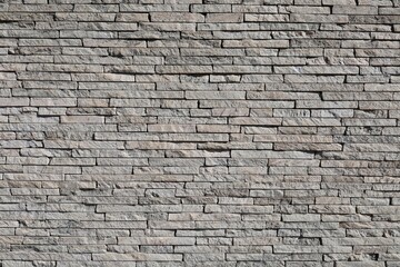 Fototapeta premium Wall made of reconstructed stone strips. Gray and brownish colors. Coating for exterior or interior. Background and texture. Full frame.
