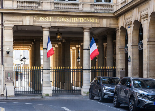 Paris, France - June 17, 2026: Portico decked with french flags in the Palais Royal, home of the Constitutional Council, the highest constitutional authority, with unmarked police cars parked in front