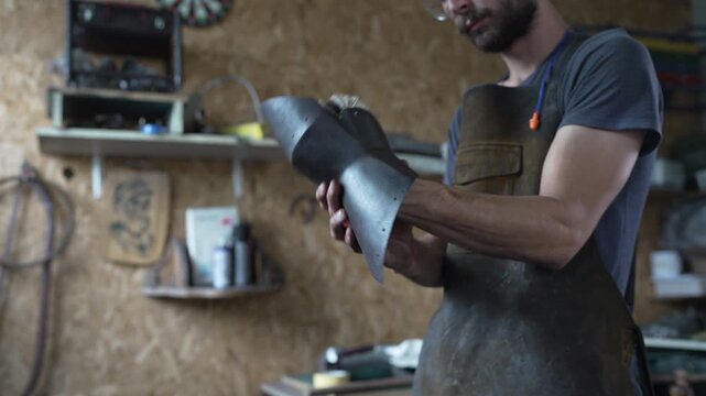Craftsman inspecting handmade medieval armor gauntlet