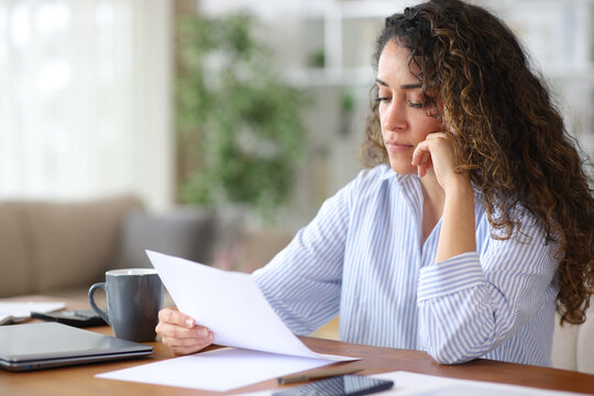 Concentrated adult teleworker reading paper form working at home