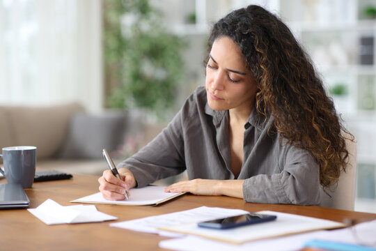 Adult teleworker writing letter working at home