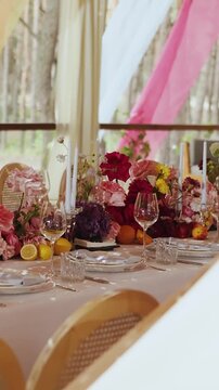Vertical video. Wedding table setting with flowers, glassware and plates indoors. No food