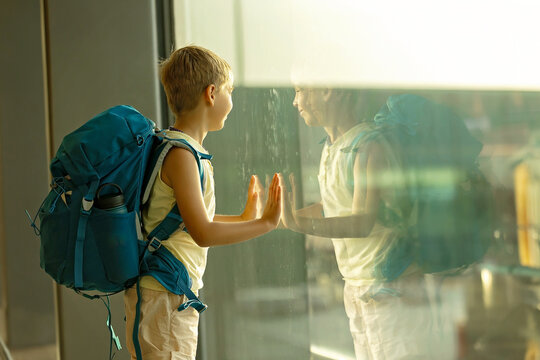 Child, watching from the window of the airport the planes, taking off and landing while waiting at  to board the aircraft