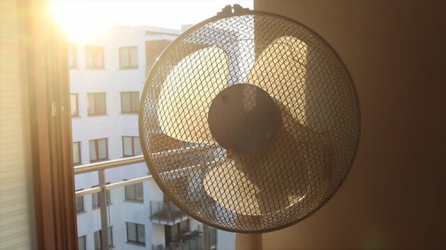 Electric fan cooling a room during an extreme summer heatwave at sunrise.