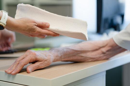 Medical hands transferring casted arm for orthopedic treatment. Healthcare professional providing care with trust, cooperation and gentleness. Bone fracture treatment in clinic treatment room