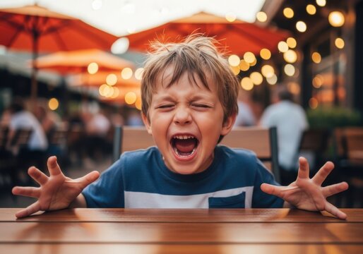 Young boy having a loud tantrum at a restaurant table
