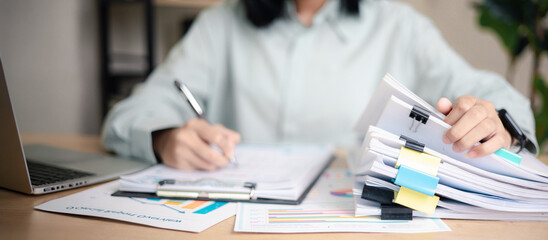 Obraz na płótnie Canvas Business professional reviewing performance reports and auditing stack of documents at office desk. Concept of corporate audit, compliance check, data analysis,