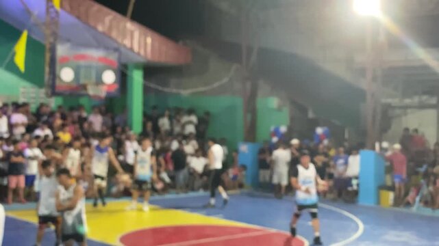 Basketball players are warming up in a round-robin format in a local league on an indoor, covered court. High angle, blurs