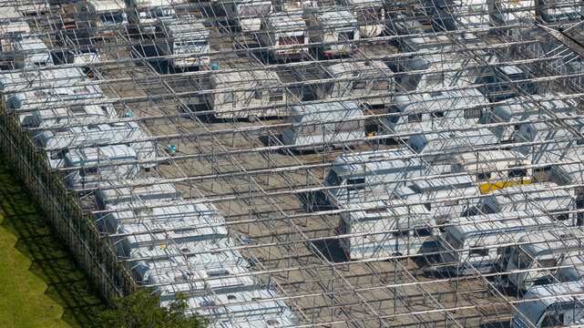 Aerial view of a caravan storage facility featuring numerous parked caravans arranged in rows under a large metal scaffolding structure in Alkmaar, North Holland, Netherlands.