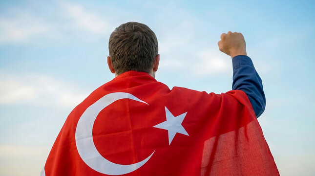 Patriotic man raising fist wearing a turkish national flag cape with celebration