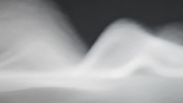 Abstract close-up of soft, flowing white and grey smoke or mist against a dark background, creating an ethereal and atmospheric composition with gentle curves.