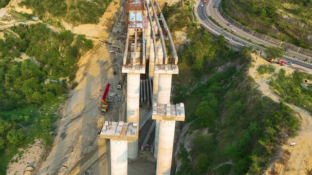 High angle aerial view of incomplete bridge deck and concrete pillars on mega construction site.