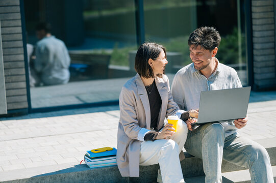 Colleagues sitting outdoors working together on a laptop