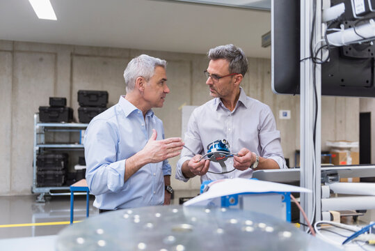 Two businessmen in factory hall examining product