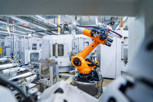 Industrial robot working in automated production hall with machinery