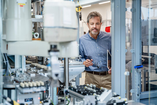 Engineer checking industrial robots in modern factory with tablet