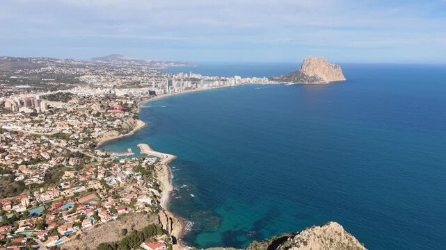 Drone pulls back from Morro de Toix viewpoint above Calpe and the Mediterranean Sea.