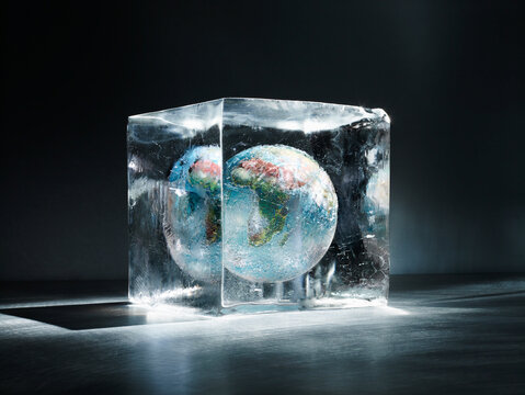 Terrestrial globe frozen inside an ice block on dark background