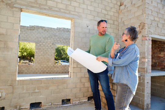 Builder and homeowner discussing plans at construction site
