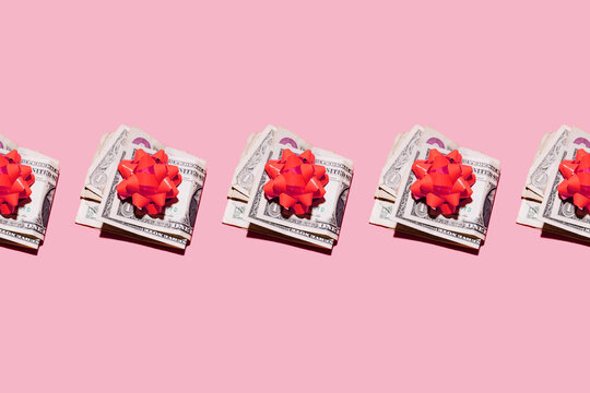 Studio shot of row of folded dollar bills with red gift bows
