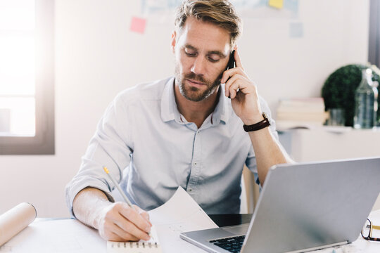 Portrait of architect on the phone at desk in his office