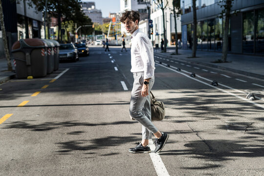 Young man in the city on the go crossing street