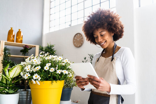 Female shop owner using digital tablet while standing at plant shop