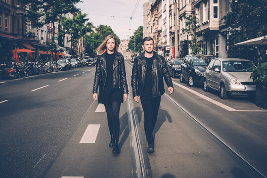 Young couple wearing black matching clothes walking side by side on the street