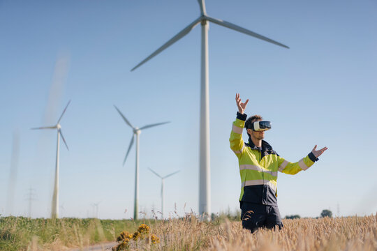 Engineer standing in a field at a wind farm wearing VR glasses
