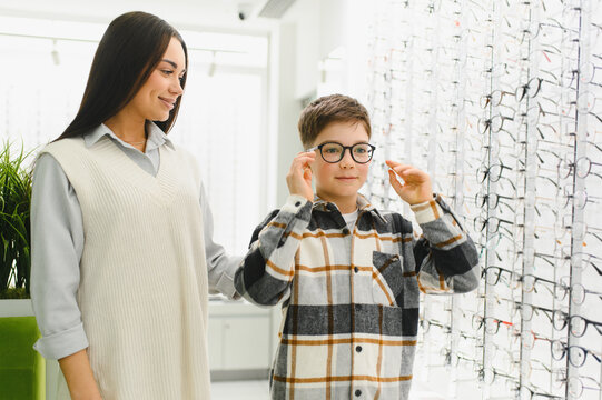 Mother and son choosing new eyeglasses in optical shop