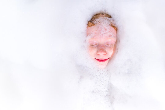 Smiling face covered in thick white bath foam