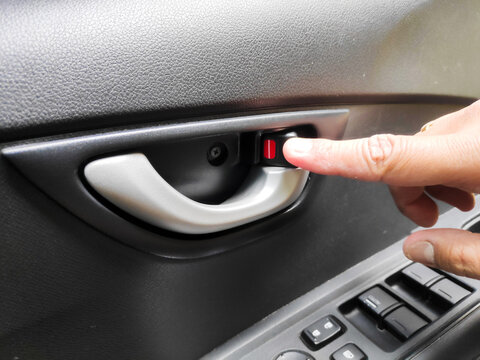 Close up of a persons hand with a gold ring pulling a silver interior car door handle to exit