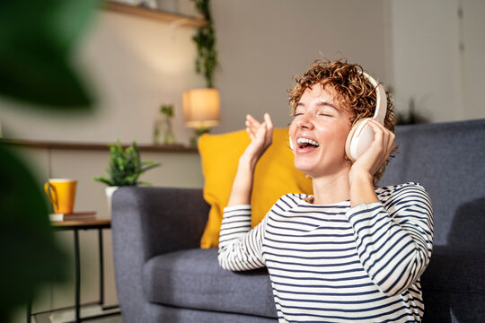 Smiling woman enjoying music with headphones in cozy living room