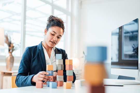 Businesswoman with toy blocks sitting at desk in office